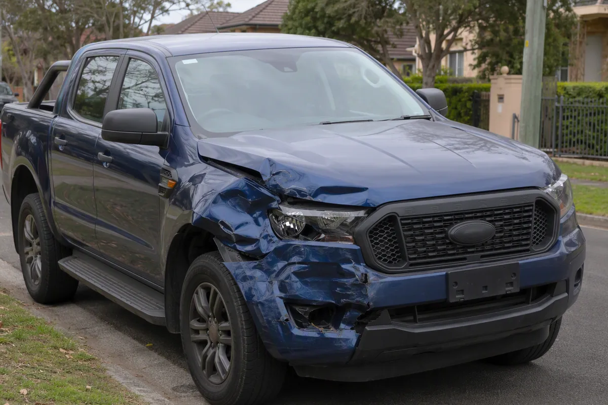 Damaged car with a crushed front corner parked on a Sydney suburban street